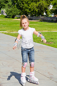 蓝色溜冰鞋摄影照片_学习溜冰鞋的女孩