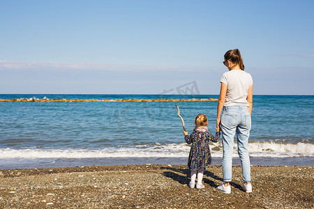 沙滩上快乐的妈妈和小女儿的背影