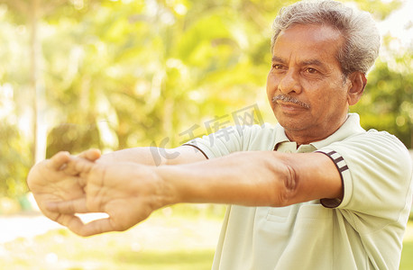老人运动前伸手 ​​— 老年人户外健身的概念 — 60 多岁的人在公园做瑜伽体式。