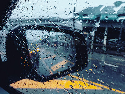 雨滴落在车玻璃上，一片模糊的景象。