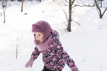 冬天、家庭、童年概念 — 正宗的学龄前小女婴，穿着粉红色保暖衣服，在公园里雪天寒冷的天气里行走。