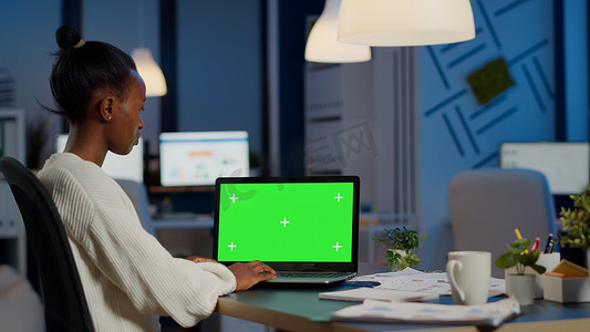 非洲经理在带色键显示加班的笔记本电脑上打字