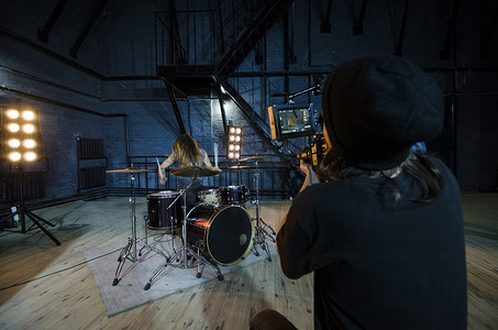 专业摄影师使用电影数字摄像机拍摄音乐视频的鼓手。