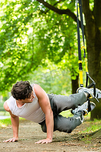 城市公园里做悬吊教练运动的人
