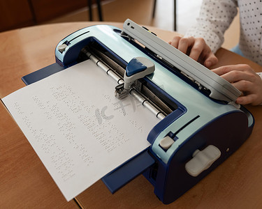 盲文打字机摄影照片_使用盲文打字机的盲人妇女。
