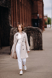 一个穿着灰色外套的快乐时尚女孩在城市里走来走去