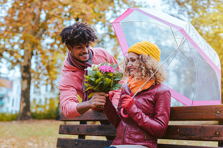 细雨蒙蒙摄影照片_在细雨蒙蒙的秋日，男人用一束鲜花给妻子一个惊喜