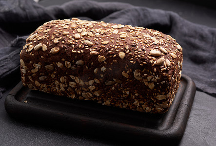 黑色背景中带燕麦片的烤方形黑麦面粉面包，顶视图