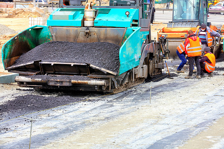 一辆辆大型沥青摊铺机和一台路面振动压路机在新沥青路面的施工中相继前行。