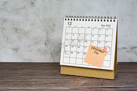2022 年 12 月的日历在木桌上，日期圈和便利贴上的文字。