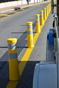 安全条纹摄影照片_沿路的黄色条纹杆划分交通方向、道路安全概念