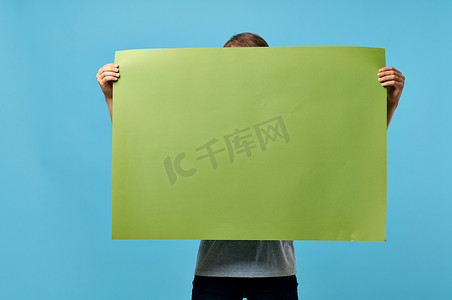 男子手持绿色横幅营销文案空间蓝色广告背景