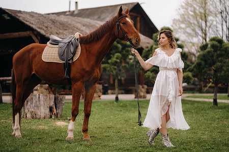一个白色太阳裙的美丽的女孩在一个老牧场的一匹马旁边