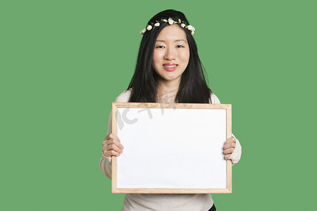 绿色背景中拿着空白白板的年轻女子的肖像