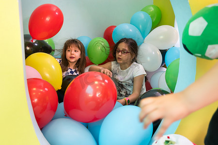 可爱聊天摄影照片_两个可爱的女孩一边玩着五颜六色的气球一边聊天