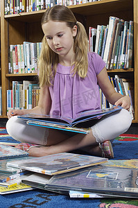 女孩坐在地板上在图书馆看书
