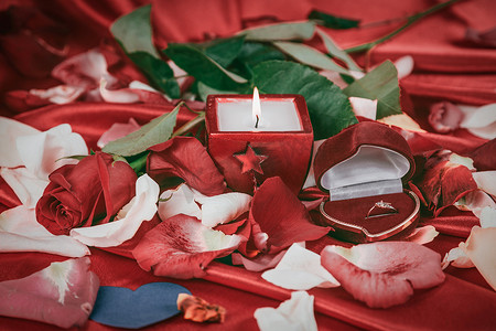 新婚玫瑰摄影照片_玫瑰花瓣背景上的蜡烛和钻戒