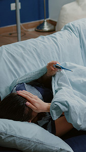 患有疾病的妇女躺在沙发上测量发烧