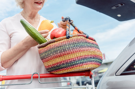 快乐的高级女人拿着装满新鲜蔬菜的篮子