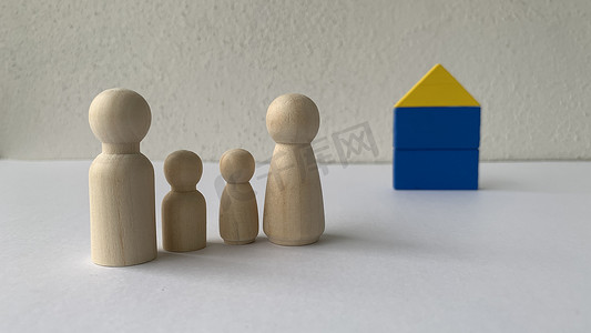 木娃娃家族站在房子模型前。