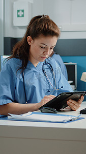 医疗助理在平板电脑屏幕上打字并检查计算机