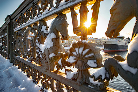 黑暗系摄影照片_这艘大船停泊在英国堤岸附近，穿过布拉戈维申斯基桥的栏杆，冬季城市圣彼得堡，太阳的灯光，系泊线，粗绳