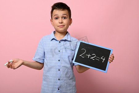 可爱的男孩，小学生拿着粉笔和黑板，解决数学问题。
