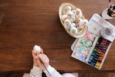 女人为复活节彩蛋节在幻想鸡蛋上画水彩的顶视图。