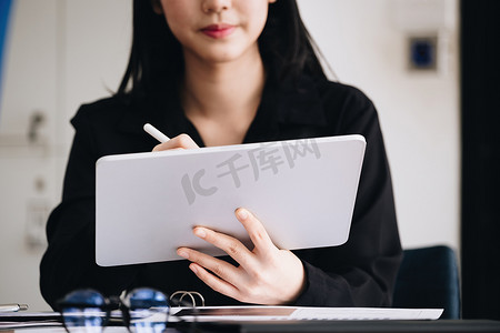 电子工作理念，女性员工正在使用平板电脑和文档分析公司利润，以提高去年的收入。