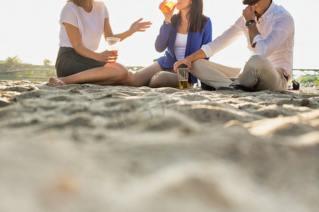 镜头光晕摄影照片_商界人士在海滩上喝啤酒庆祝成功，背景是镜头光晕
