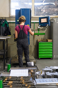 工业口罩摄影照片_在现代金属工业工作和使用钻头时因冠状病毒流行而戴口罩的妇女