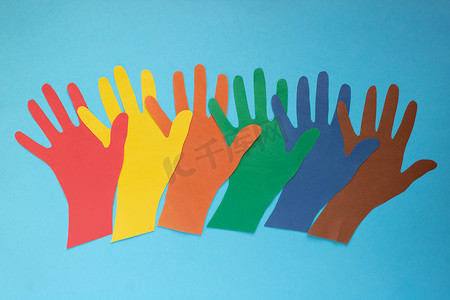 抽象背景在蓝色背景上打开五颜六色的纸手掌。自闭症日和青年团结日的概念