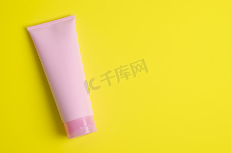 在绿色背景上用空白空间清空化妆品粉红色管奶油。