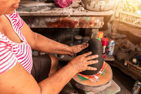 尼加拉瓜莱昂拉巴斯中心一位雕塑工匠手上的特写，他把一个粘土娃娃拼在一起出售