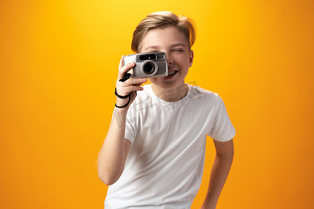 黄色背景中带着旧相机的小男孩