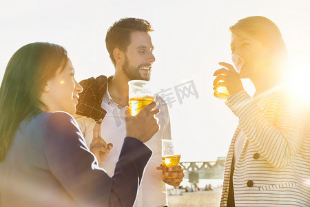 镜头光晕摄影照片_商界人士在海滩上喝啤酒庆祝成功，背景是镜头光晕