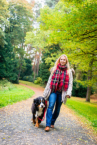 遛狗的女人摄影照片_在公园里用皮带遛狗的女人