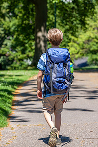 背着巨大背包在公园徒步旅行的男孩