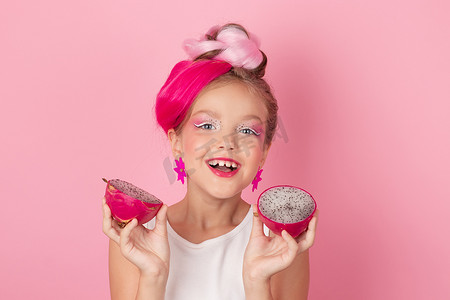 红色火龙果摄影照片_粉红色发型的漂亮女孩的特写肖像，粉红色背景上有火龙果。