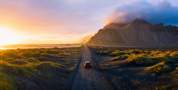 冰岛日落时的碎石路与 Vestrahorn 山和汽车行驶