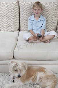男孩和宠物狗坐在沙发上看电视