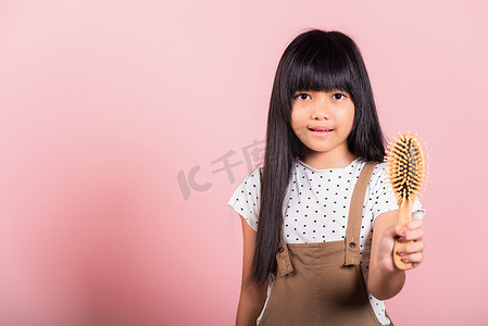 10 岁的亚洲小孩拿着梳子不守规矩地刷她，她摸着她长长的黑发