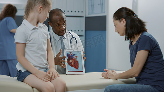 医生在平板电脑上向妇女和儿童展示心脏图像