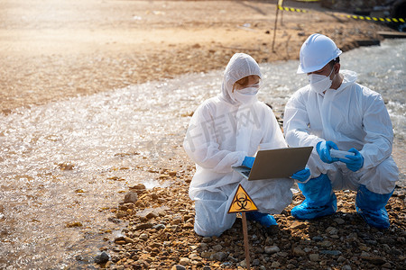 生物学家穿防护服和面具从工业收集废水样本