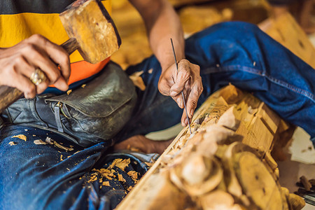 装箱大师摄影照片_木雕大师使用特殊的刀制作了木制国菜——带图案手柄的勺子。