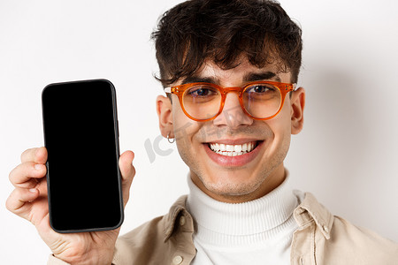 戴眼镜的帅气微笑男人的脸，显示空的智能手机屏幕，白色背景