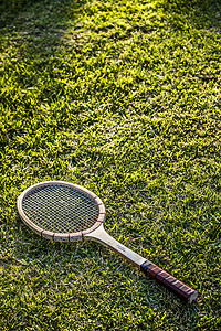绿草花园上的老式木网球拍