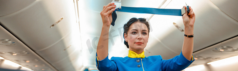 有安全带的女空姐站在飞机机舱里