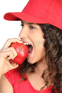 戴红帽的布鲁内特咬苹果