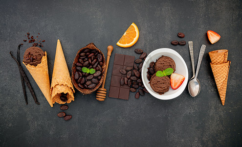 碗中的巧克力冰淇淋口味，黑巧克力和可可粒设置在深色石头背景上。
